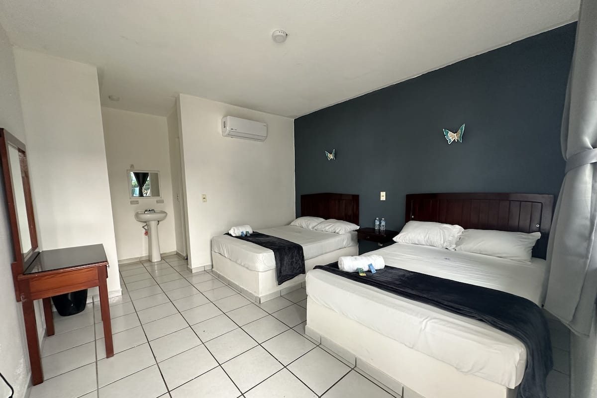 Une chambre d’hôtel avec deux lits, un bureau, un lavabo et un appareil de climatisation.