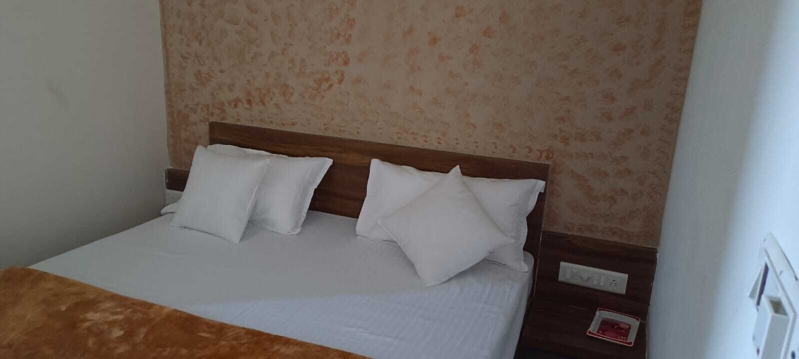 A bed with a wooden headboard, white bedding, and a brown throw blanket.