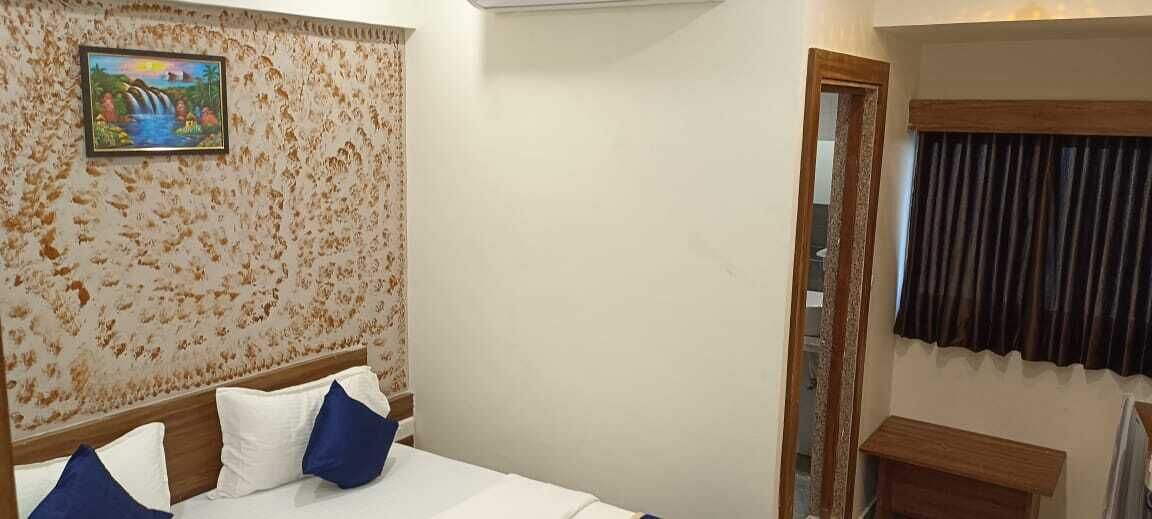 Une chambre d’hôtel avec un lit, un tableau au mur et une fenêtre avec des rideaux.