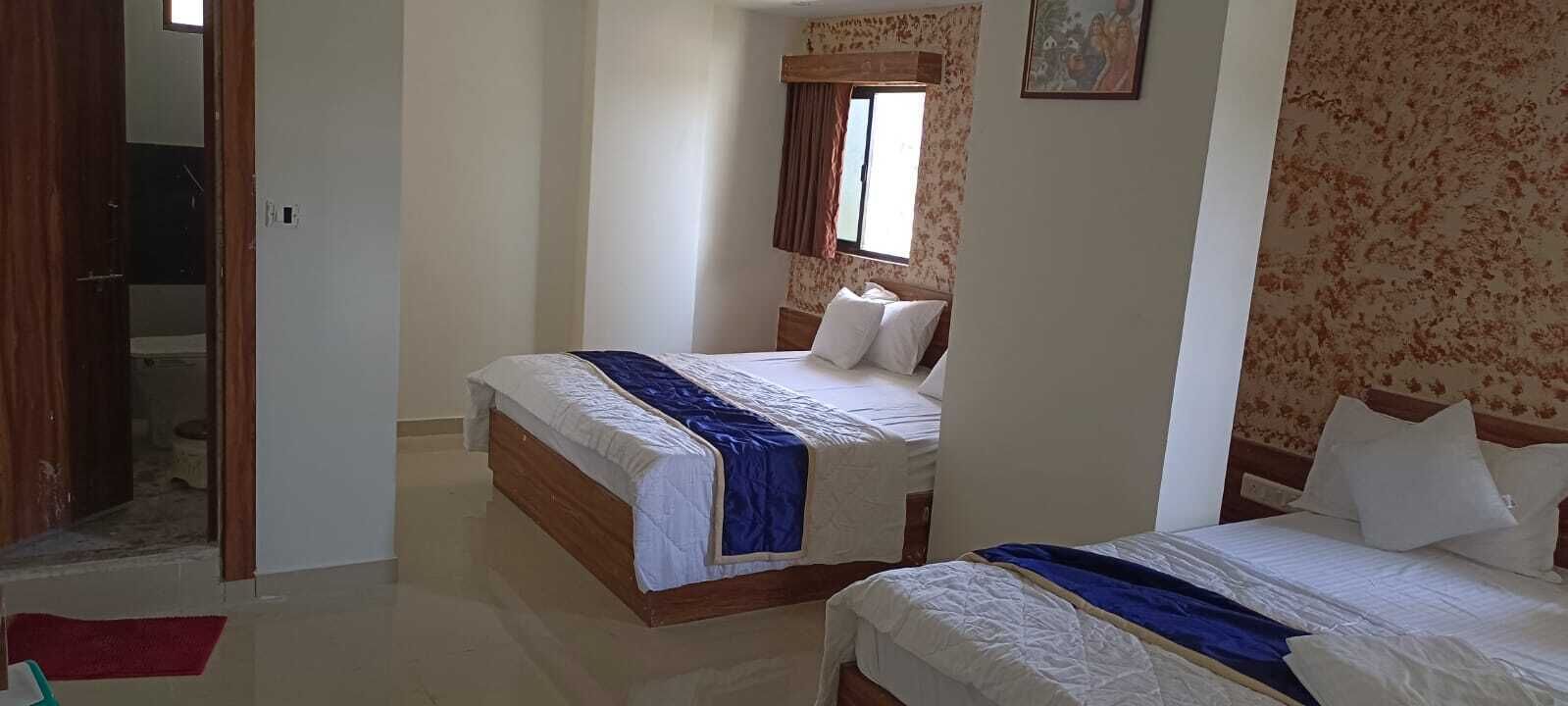 A hotel room with two beds, a wooden headboard, and a window with curtains.