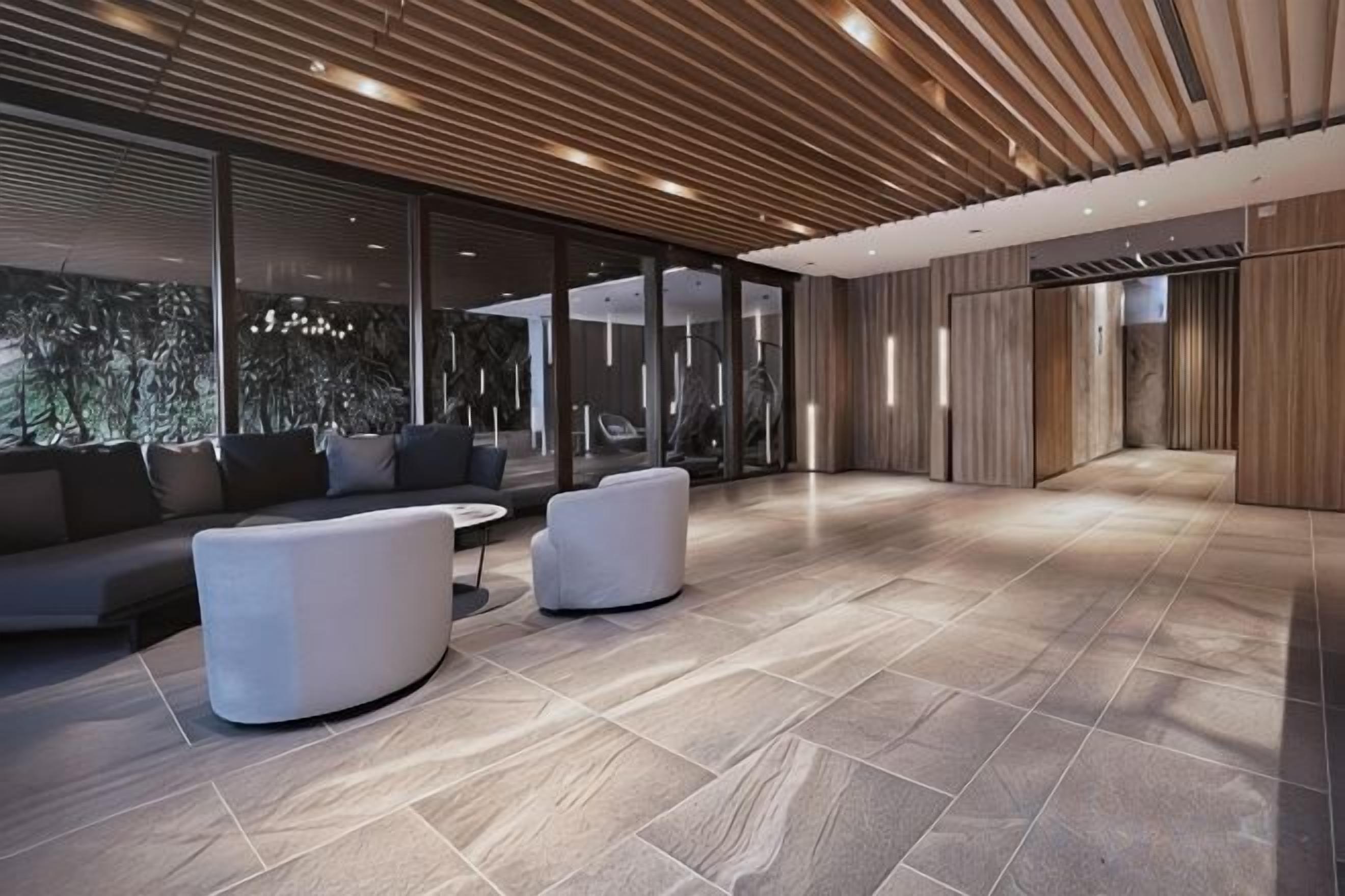 Un'ampia hall dall'arredamento moderno, con un'area salotto dotata di divani e poltrone, un ampio spazio aperto e grandi finestre che garantiscono luce naturale.