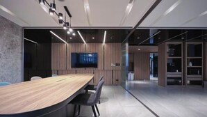 A modern conference room with a long wooden table, black chairs, and a flat-screen TV mounted on the wall. - Boutech Jiantan Hotel (Taipei)