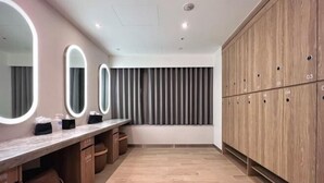 A modern bathroom with a vanity, mirrors, and a wooden cabinet with lockers. - Boutech Jiantan Hotel (Taipei)