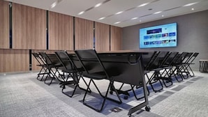 A conference room with a long table, black chairs, a large screen, and wooden paneling on the walls. - Boutech Jiantan Hotel (Taipei)