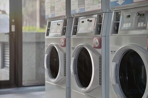 Una hilera de lavadoras industriales con paneles de control e instrucciones.