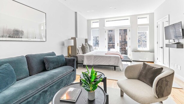 A modern living room with a sofa, armchair, and a coffee table with a plant. - Luxe Studio with Charming Juliet Balcony (New York)