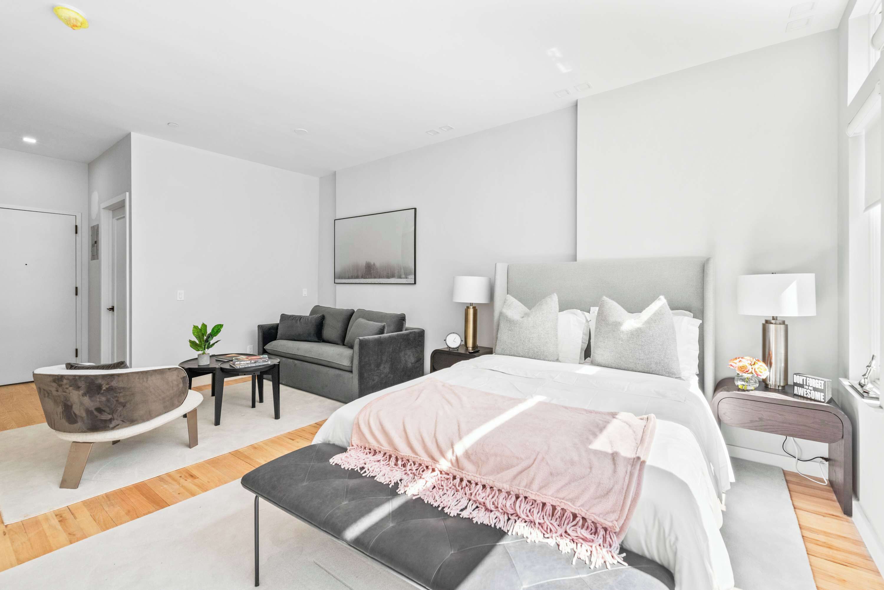 Ein modernes Schlafzimmer mit einem großen Bett, Nachttischen, einem Sofa und einem Sessel.