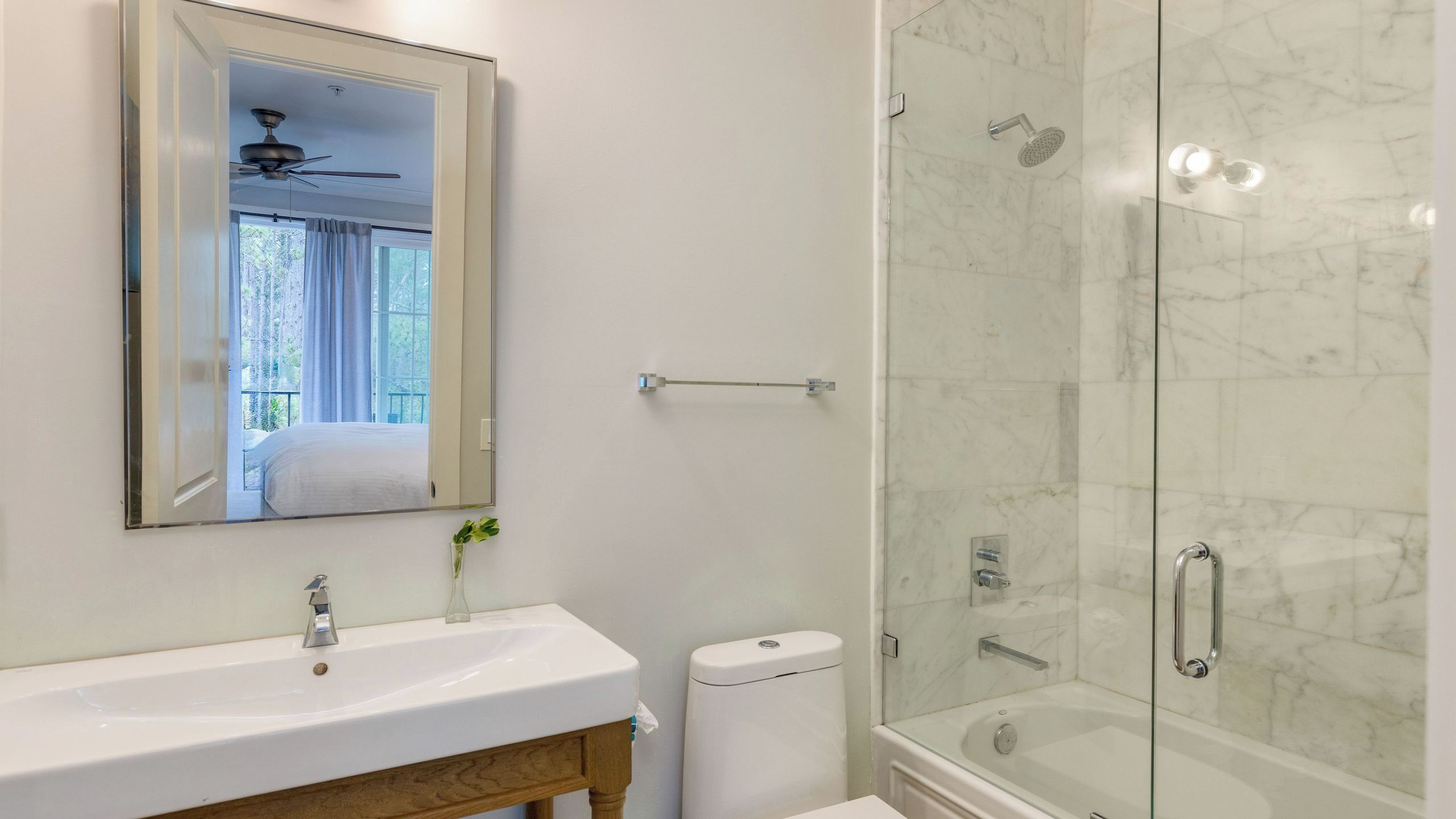 A bathroom with a sink, mirror, shower, and toilet.