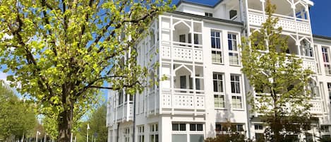 A multi-story building with a white facade, large windows, and balconies.