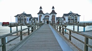 Eine Steg, der zu einem weißen Gebäude mit vielen Fenstern und zwei Türmen führt, wahrscheinlich ein Hotel oder Restaurant.