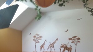 Makuuhuoneessa on sänky, yöpöytä, tuoli ja seinämaalaus.