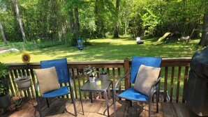 Eine Terrasse mit zwei blauen Stühlen, einem kleinen Tisch und einem Blumentopf.
