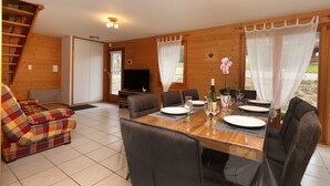 Un intérieur en bois avec une table à manger dressée pour quatre personnes, un canapé et un téléviseur placé dans un coin.