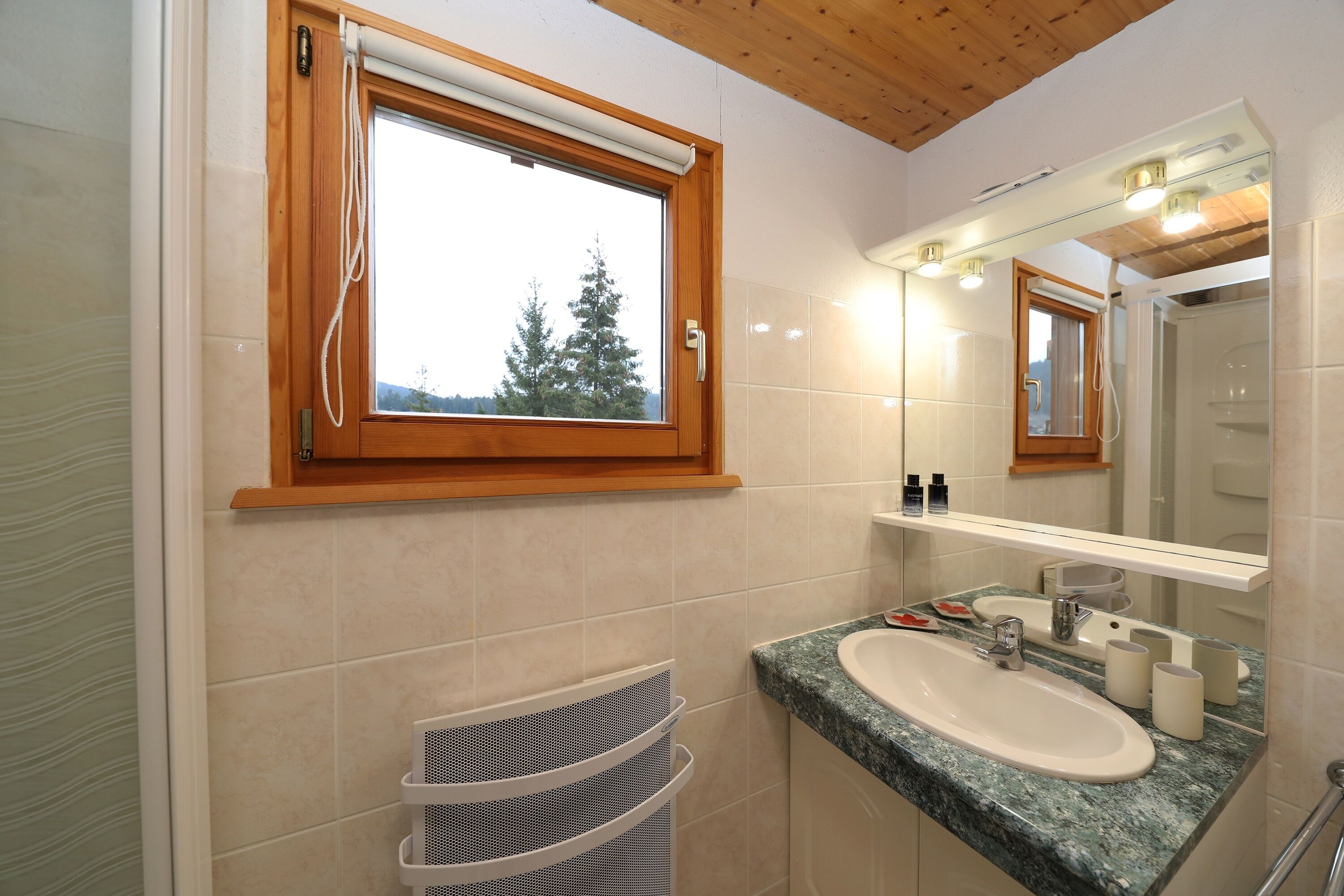 A bathroom with a wooden window, a sink, a mirror, and a towel rack.