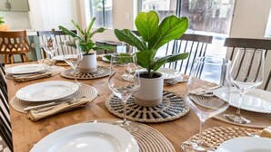 A dining table set with plates, cutlery, and glassware, with woven placemats and potted plants. - Designer Home with Chef's kitchen, Walking Trails (Flagstaff)