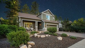 A two-story house with a stone foundation, a garage, and a well-maintained front yard with rocks and shrubs. - Designer Home with Chef's kitchen, Walking Trails (Flagstaff)