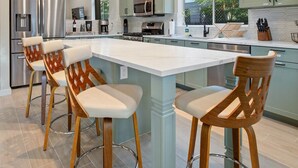 A modern kitchen with a central island, bar stools, stainless steel appliances, and pendant lighting. - Designer Home with Chef's kitchen, Walking Trails (Flagstaff)