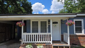 Une maison avec un porche, des fondations en briques, une porte d’entrée et une boîte aux lettres.