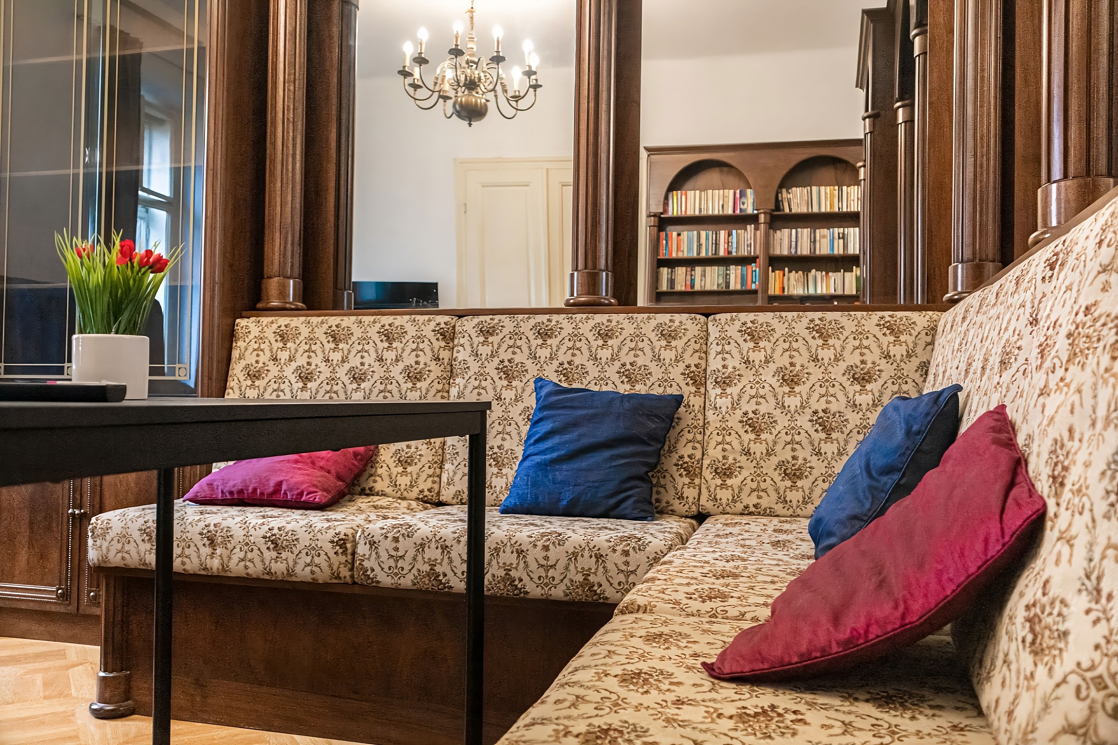 A living room with a patterned sofa, a table, and a bookshelf.