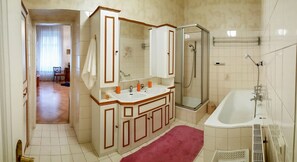 A bathroom with a shower, a bathtub, and a sink with a mirror.