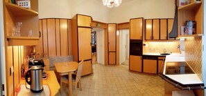 A compact kitchen with wooden cabinets, a dining area with a table and chairs, and a kitchenette with a stove and sink.