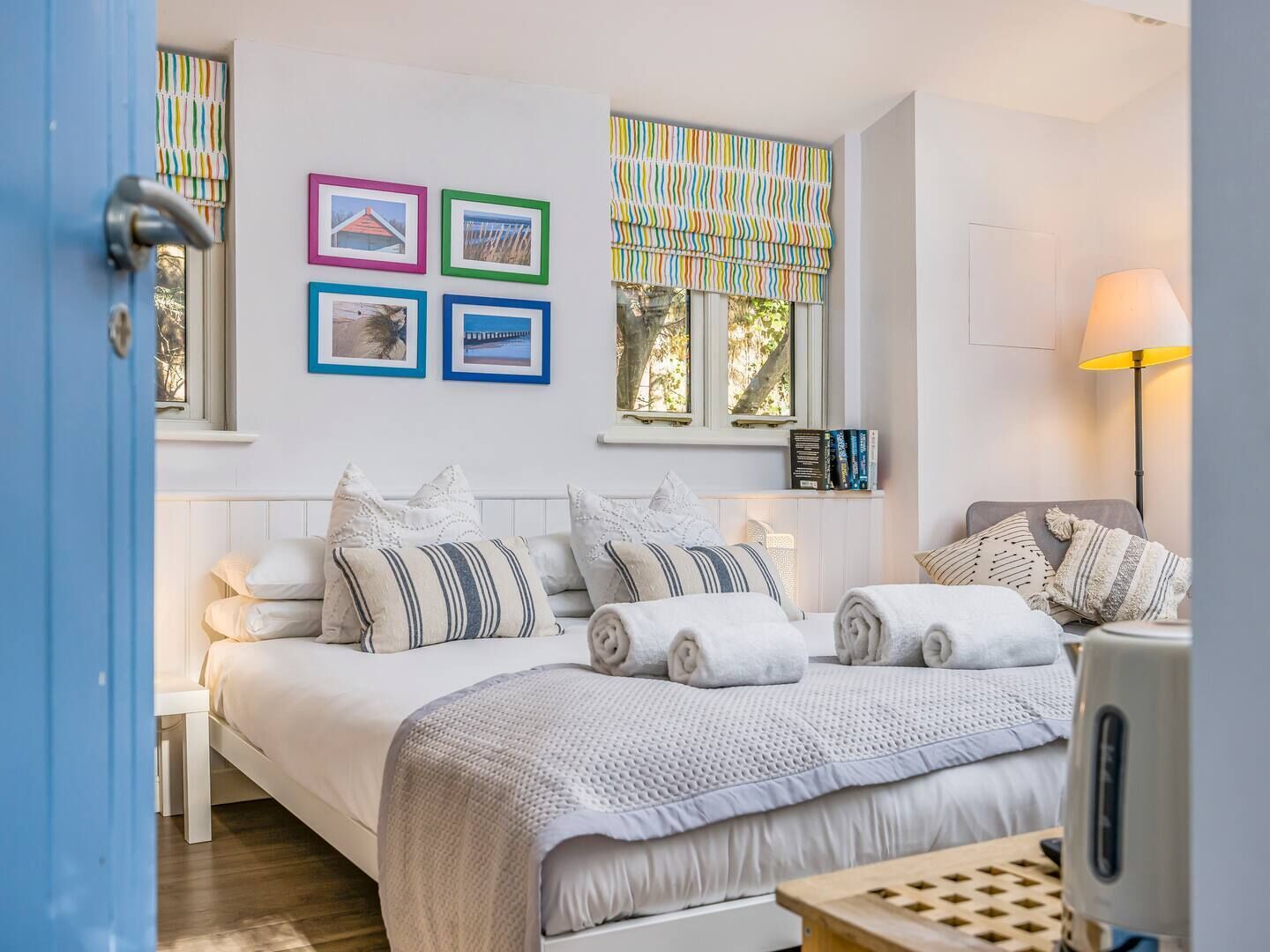 Une chambre avec deux lits, une fenêtre avec des rideaux à rayures et des tableaux encadrés accrochés au mur.