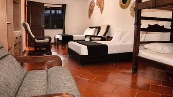 A room with a bed, two chairs, a sofa, and a wooden wardrobe.