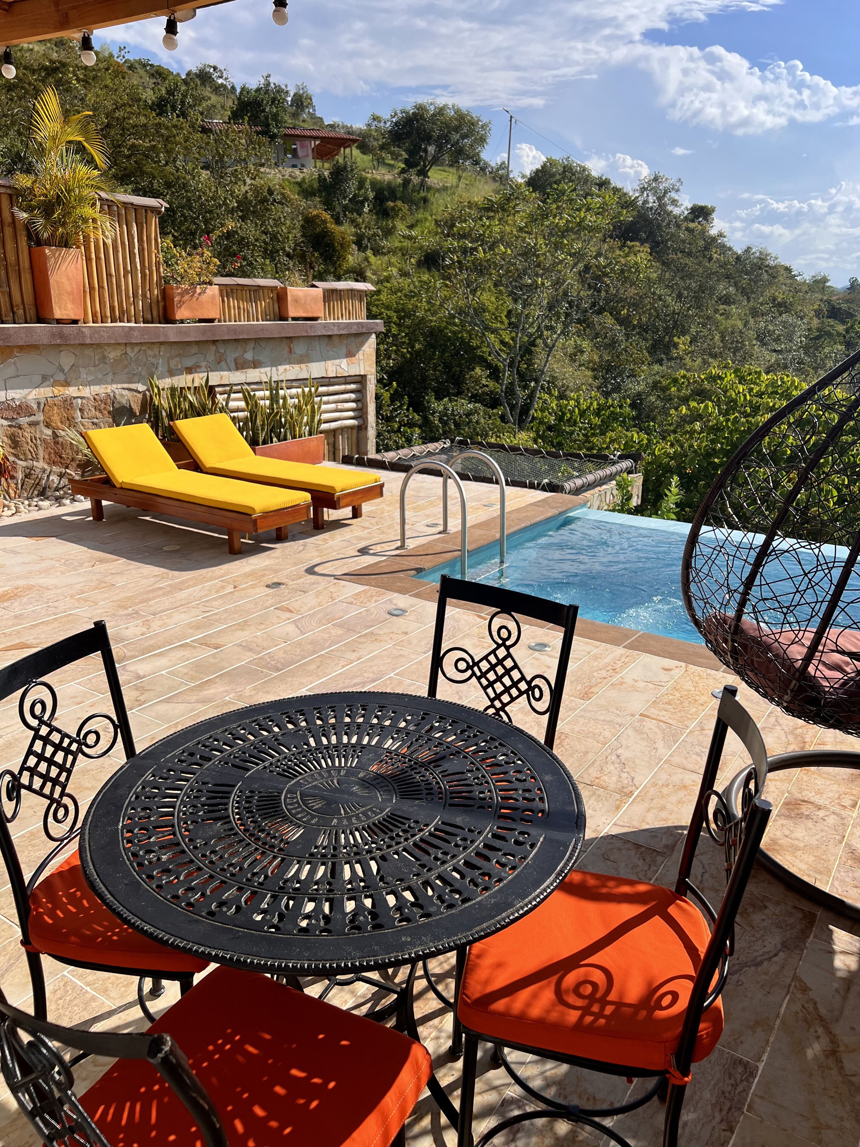 Un espace aménagé au bord de la piscine, avec une table et des chaises, un jacuzzi et des chaises longues.