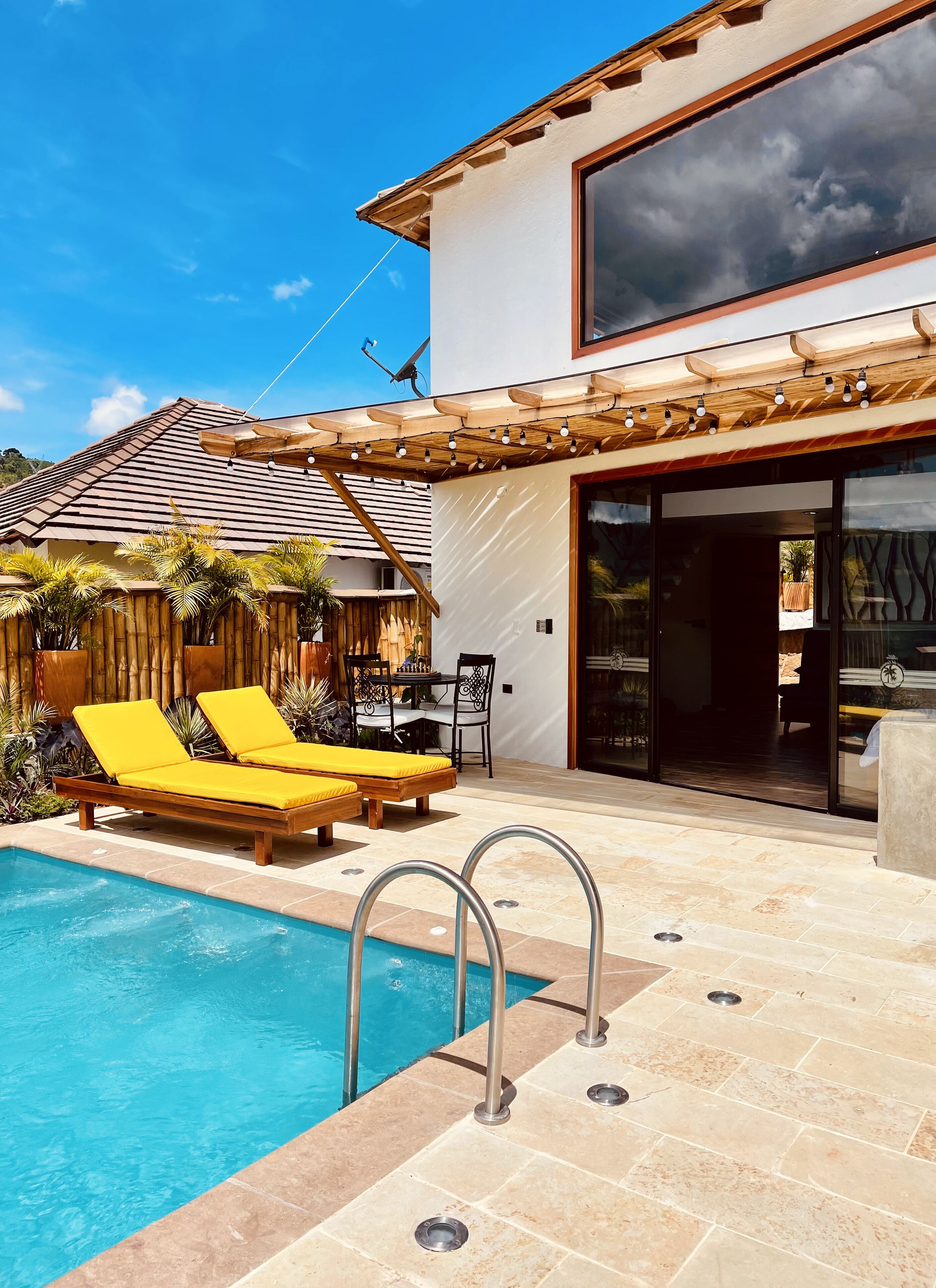 A modern house with a swimming pool, wooden deck, and outdoor furniture.