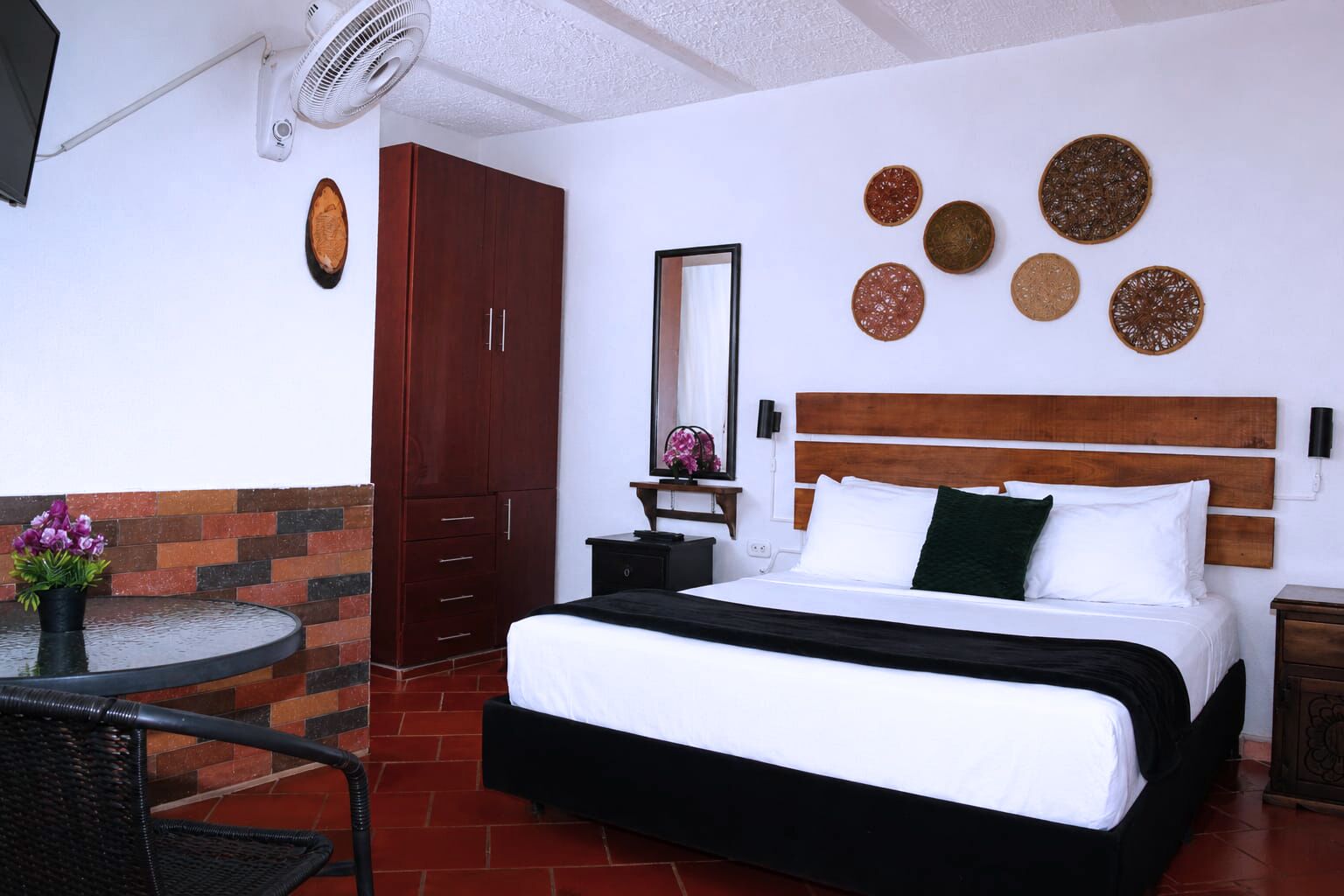 Una habitación de hotel con cama, armario, espejo y decoración mural.
