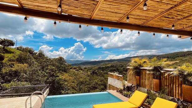 Zona de piscina con una pérgola de madera, vistas despejadas del paisaje y un área de descanso junto a la piscina.