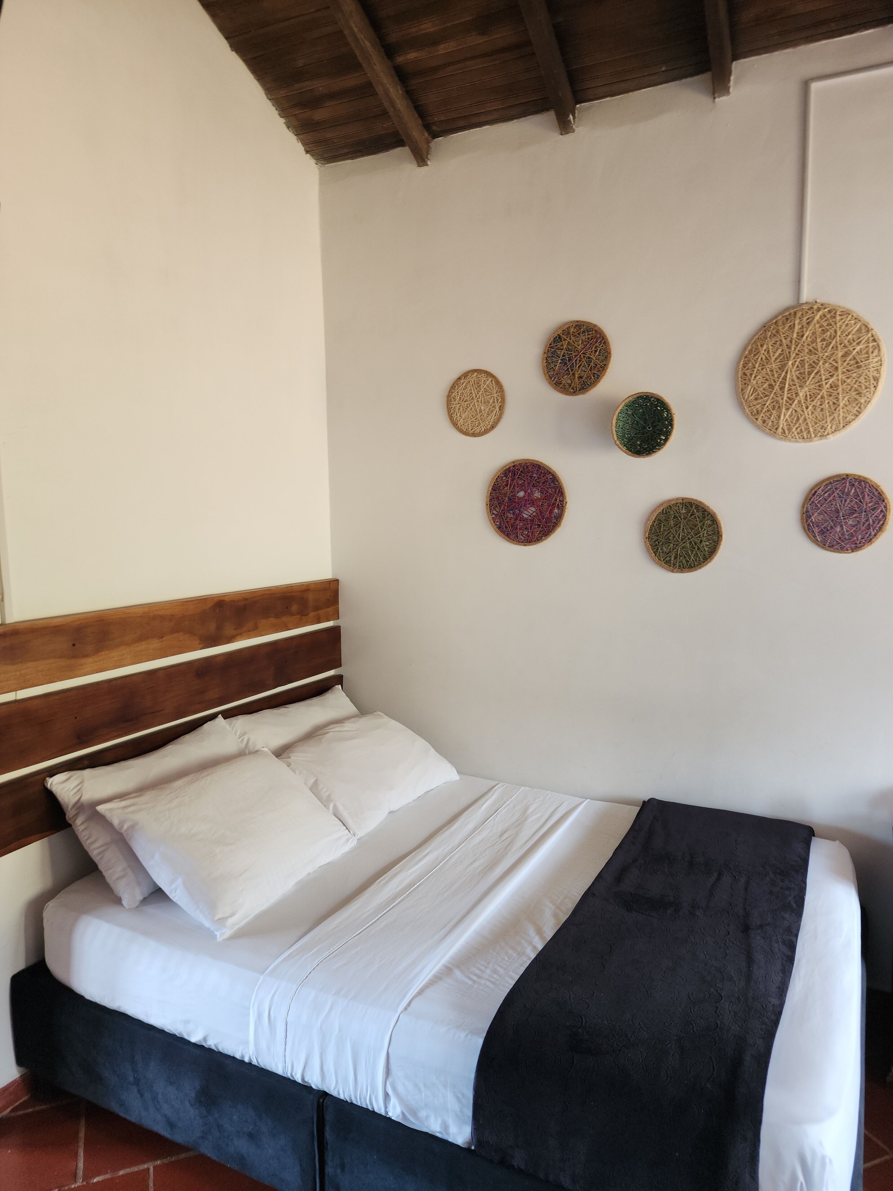 Een bed met wit en zwart beddengoed, een houten hoofdbord en een zwarte plaid.