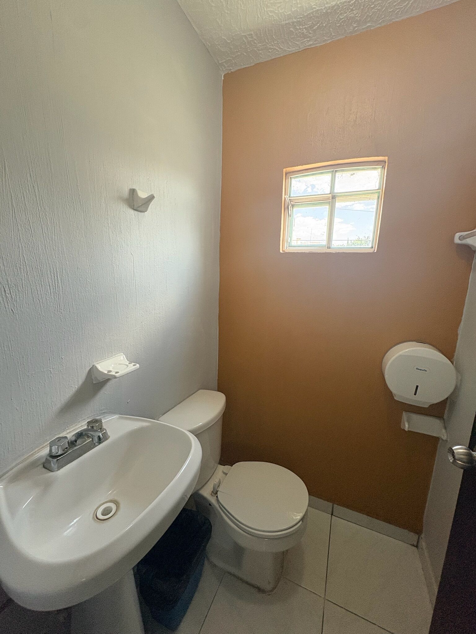 A bathroom with a toilet, sink, and window.