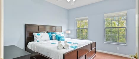 A bedroom with a wooden bed, two windows, a ceiling fan, and a nightstand.