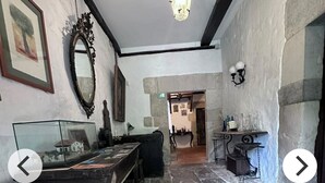 A room with stone flooring, a wooden bench, a mirror, and a hanging light fixture.