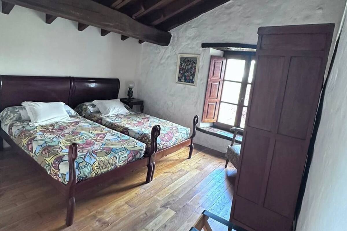 Une chambre à coucher avec deux lits en bois, une armoire en bois et une fenêtre donnant sur un paysage agréable.