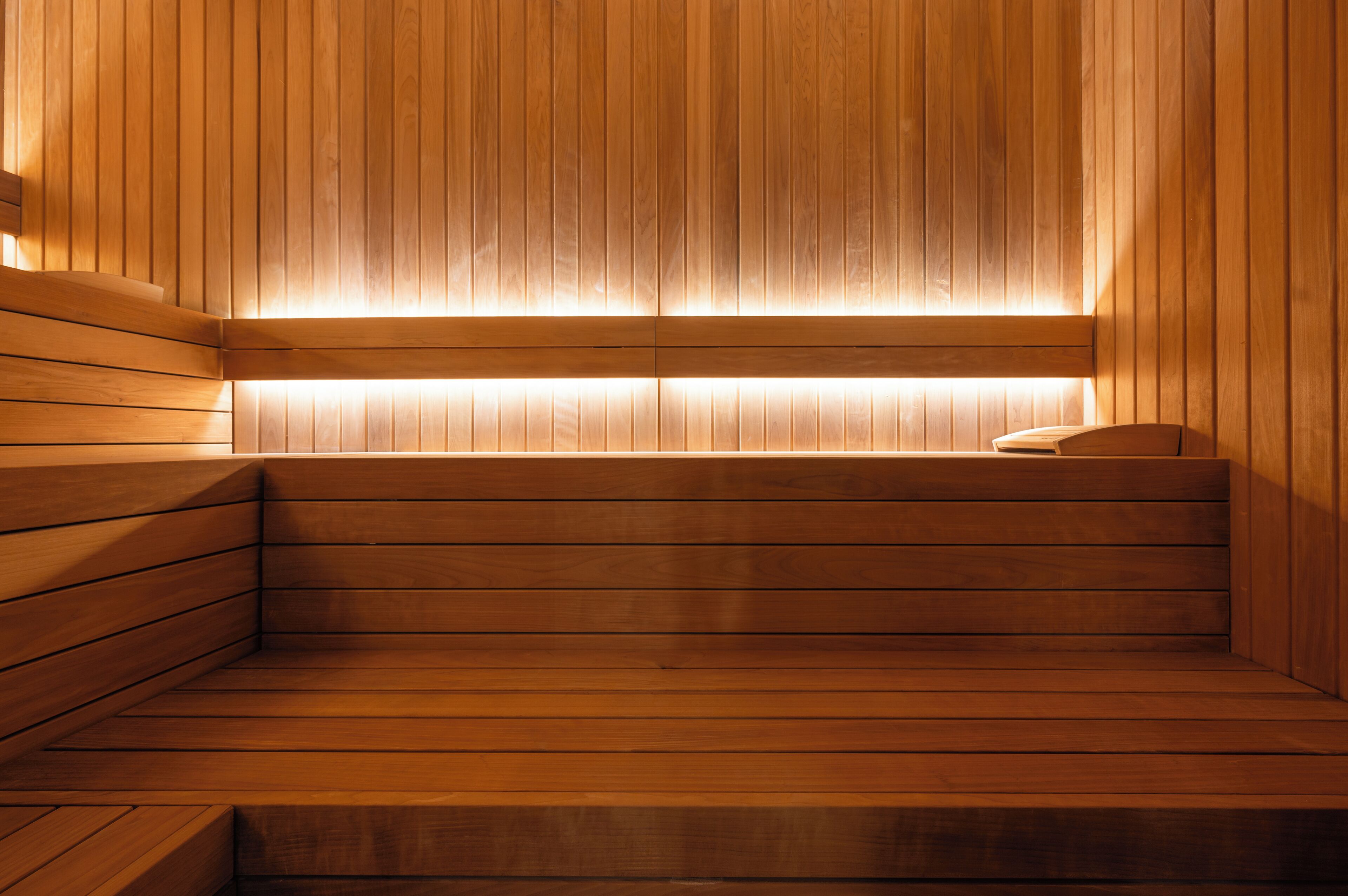 A wooden sauna with benches and a sloped ceiling.