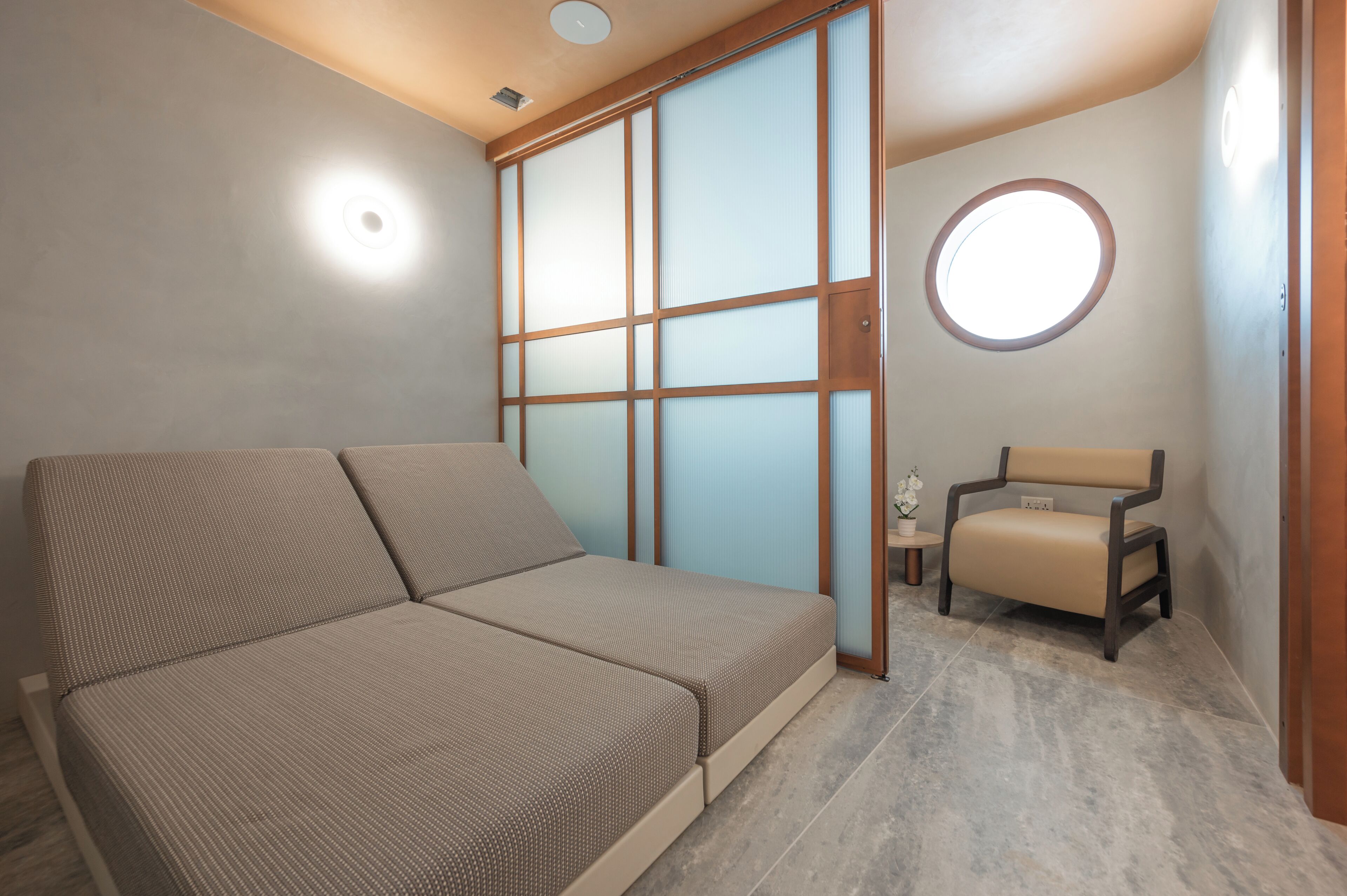 A room with a sofa, a chair, a sliding door, and a small table with a plant.