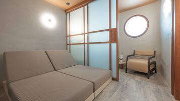 A room with a sofa, a chair, a sliding door, and a small table with a plant.