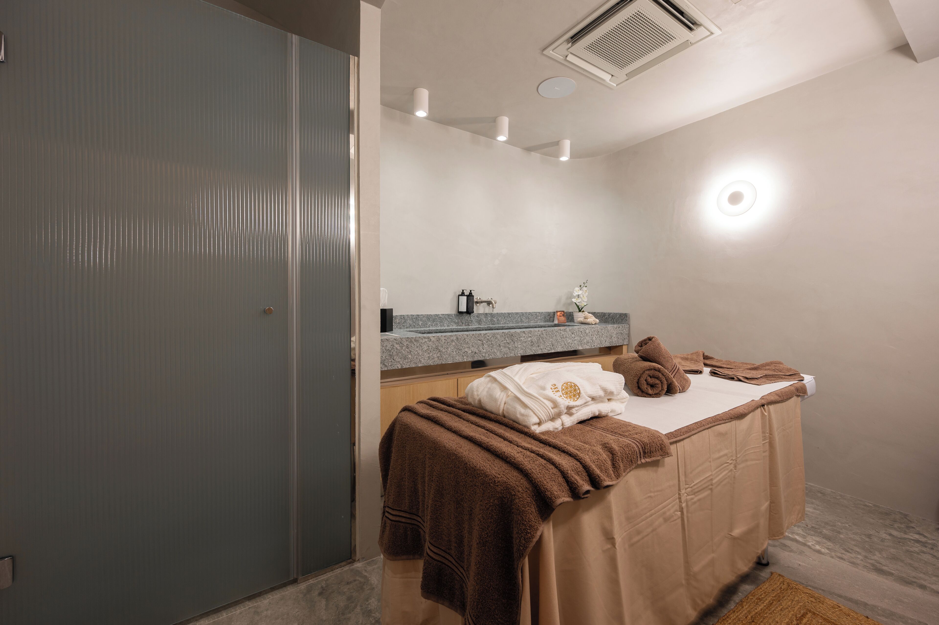 Un baño moderno con ducha, tocador con espejo y toallas sobre una cama.