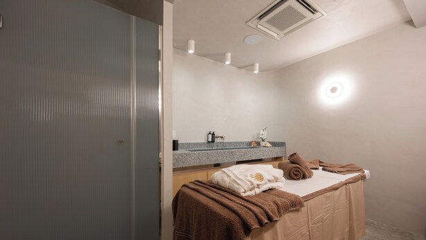 Un baño moderno con ducha, tocador con espejo y toallas sobre una cama.
