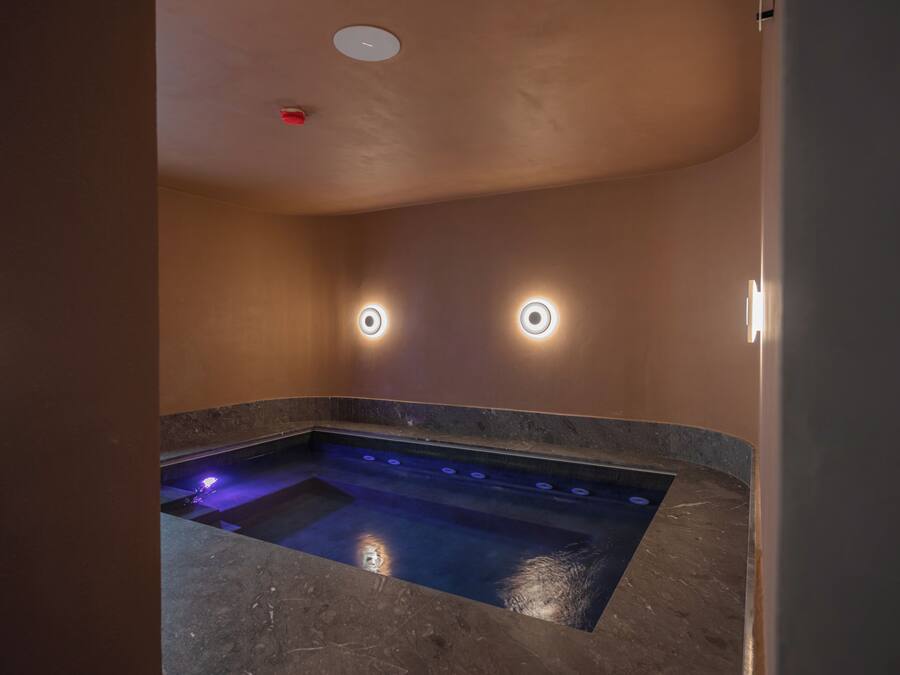 Un espace bien-être comprenant un jacuzzi, un éclairage encastré et un sol en marbre.