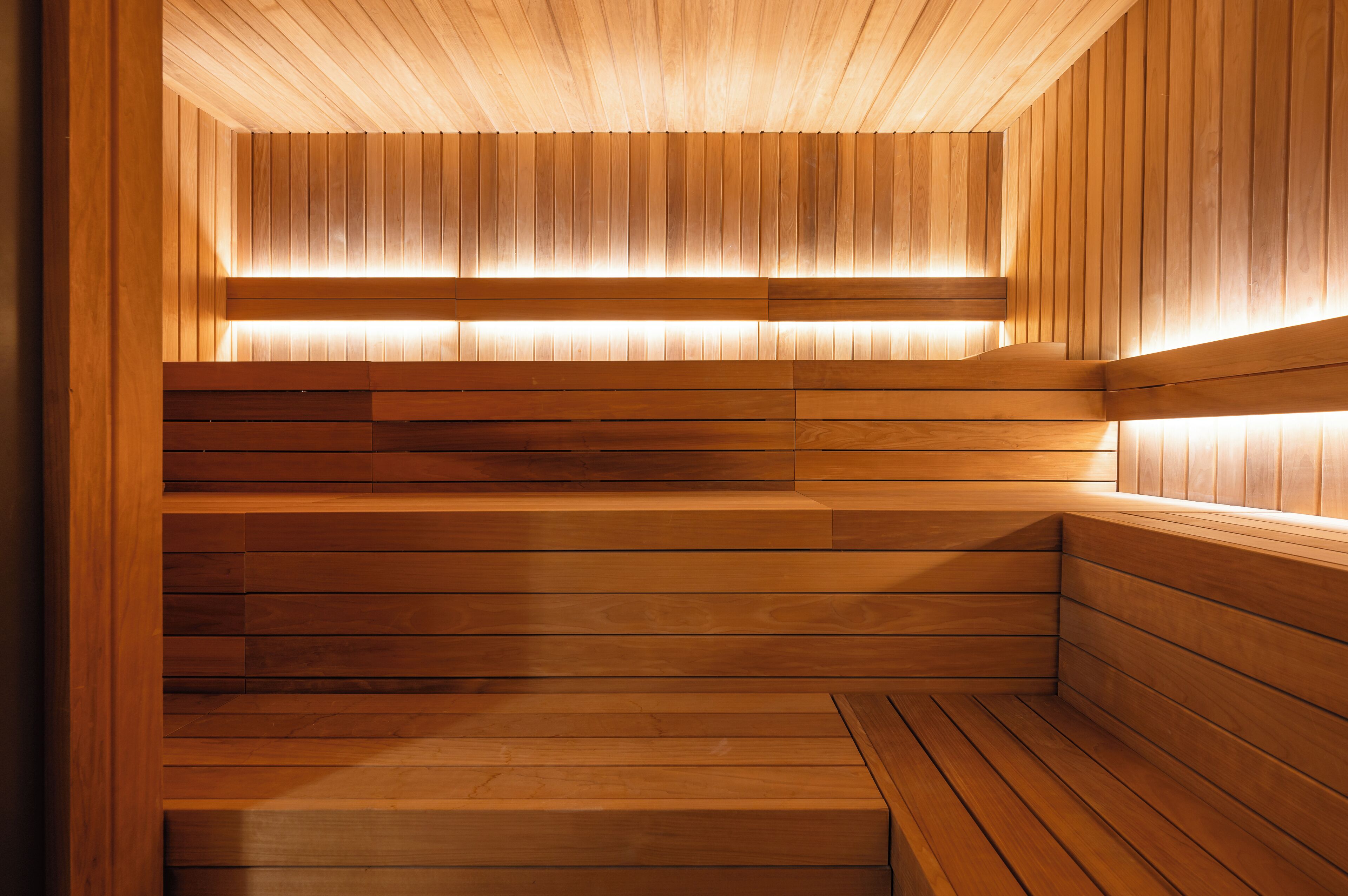 A wooden sauna with tiered seating and built-in lighting.