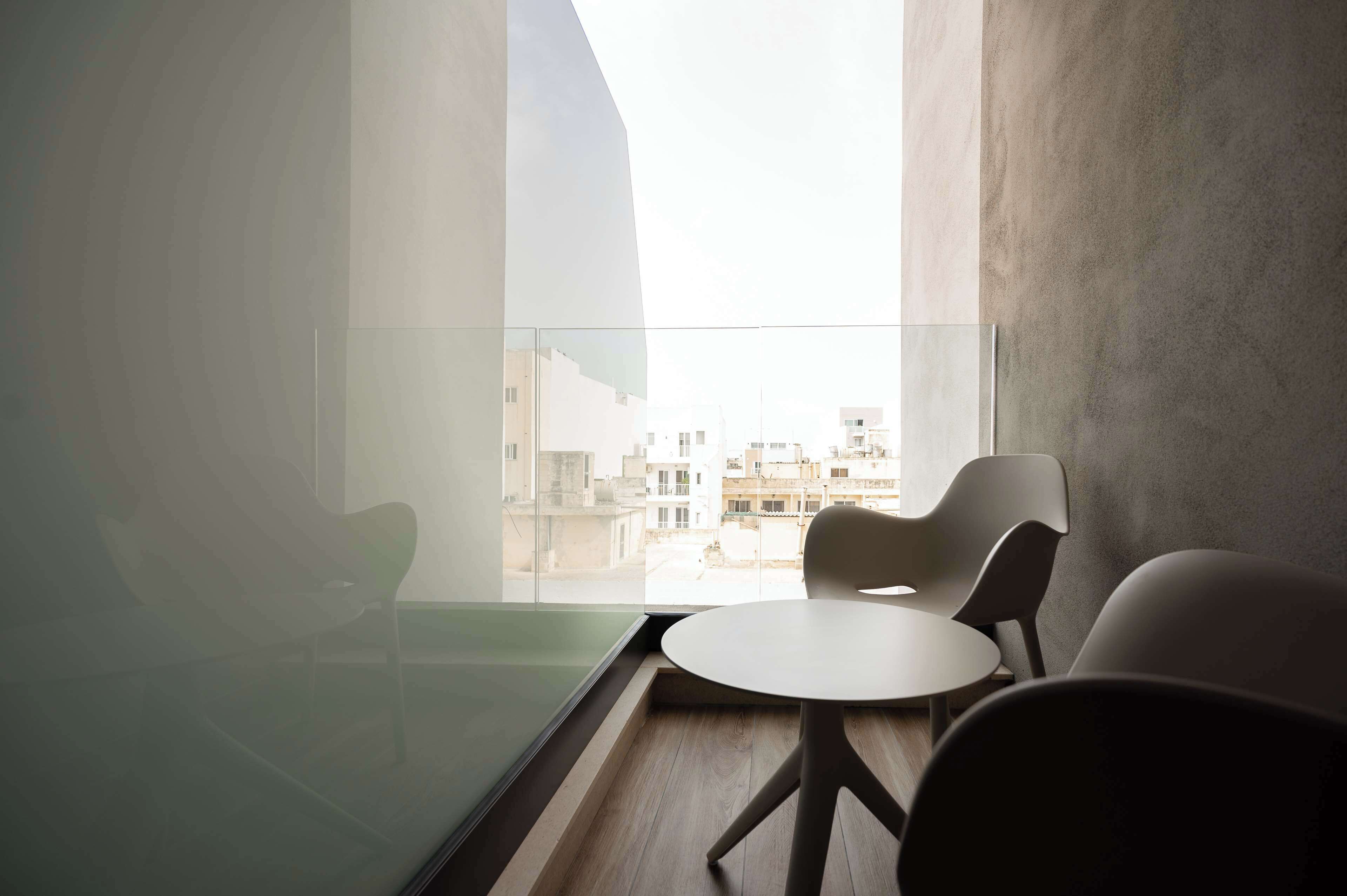 A modern room with a glass balcony, a round table, and two chairs.
