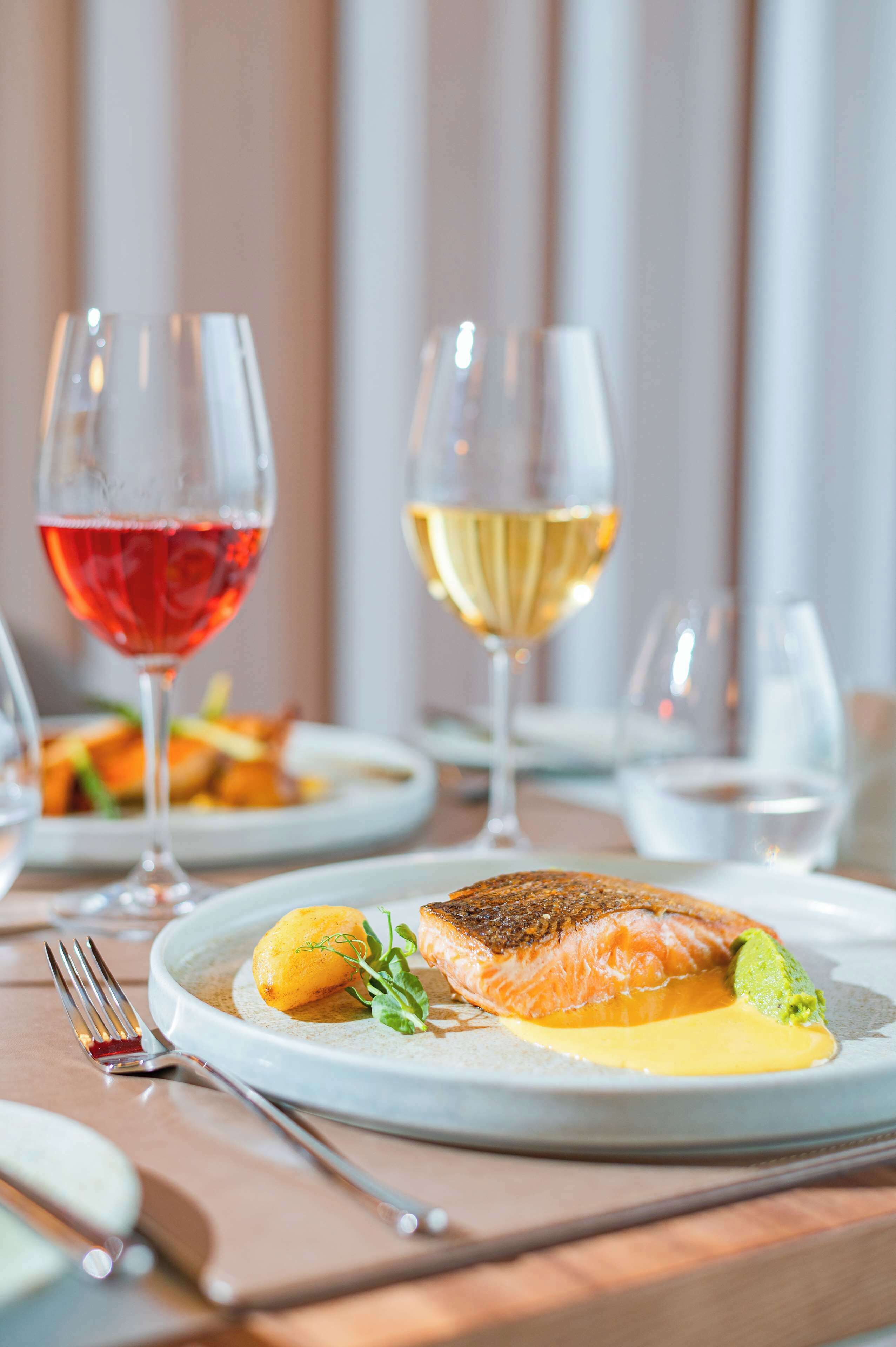 A dining table with plates of food, glasses of wine, and cutlery.