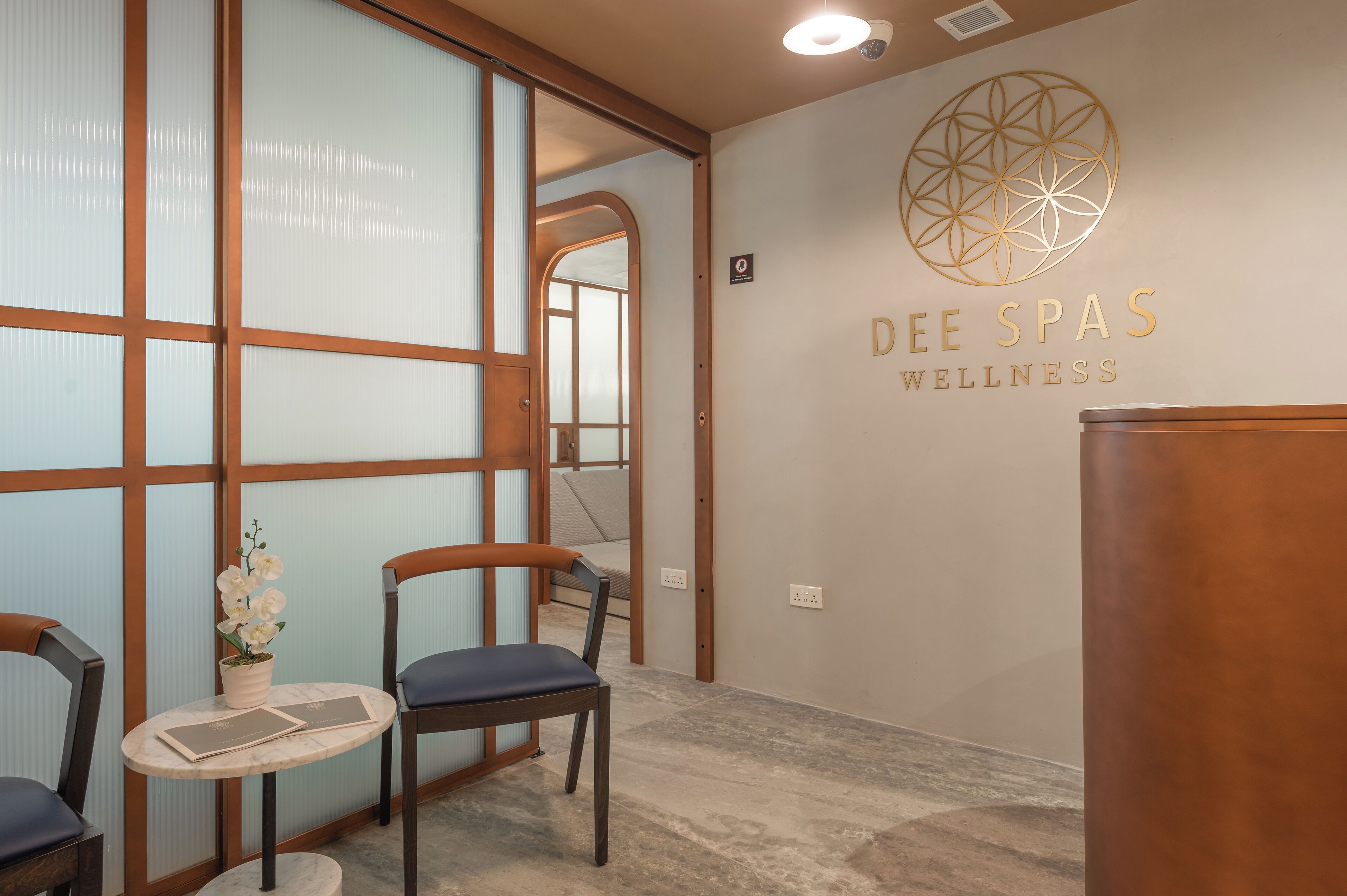 Ein Spa-Innenraum mit Empfangstresen, Sitzgelegenheiten und einer Wand mit dem Namen und dem Logo des Spas.