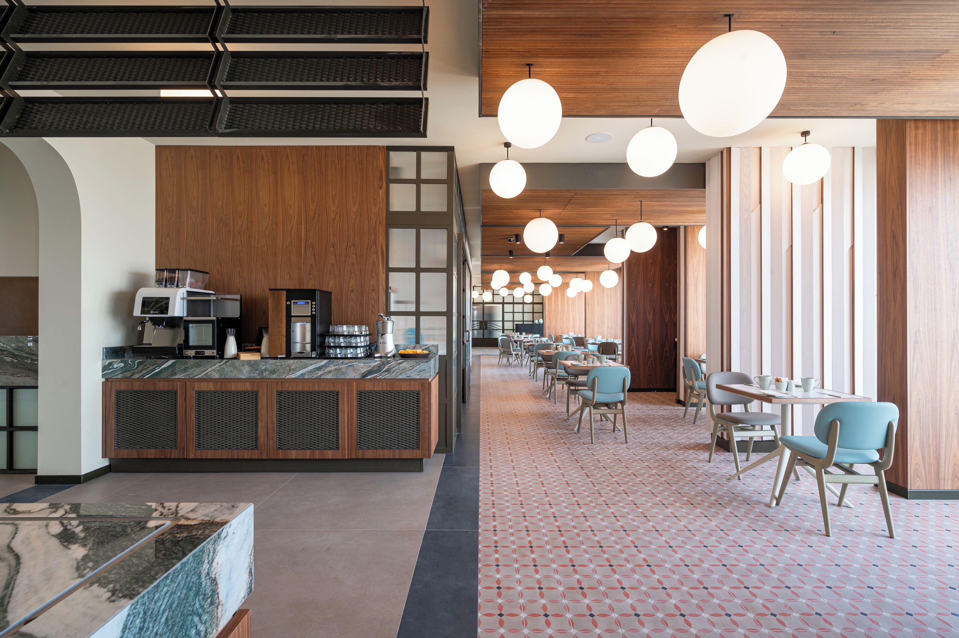 A modern restaurant with a long counter, seating area, and pendant lighting.