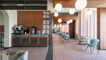 A modern restaurant with a long counter, seating area, and pendant lighting.