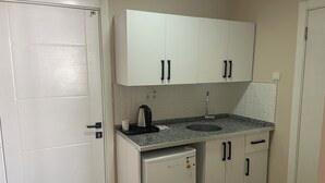 A compact kitchen with white cabinets, a built-in sink, and a small refrigerator. -  Avio Hotel (Diyarbakir)