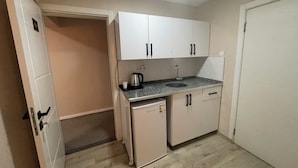 A compact kitchen with white cabinets, a sink, and a small refrigerator. -  Avio Hotel (Diyarbakir)